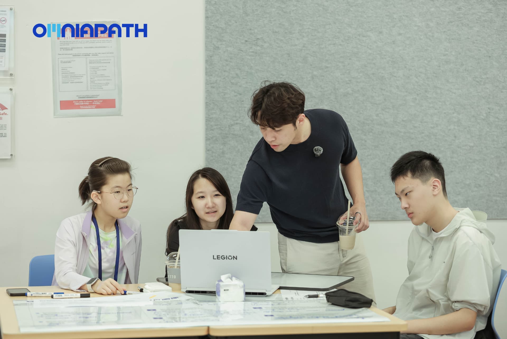 A mentor coaching a student team around their laptop and launch materials