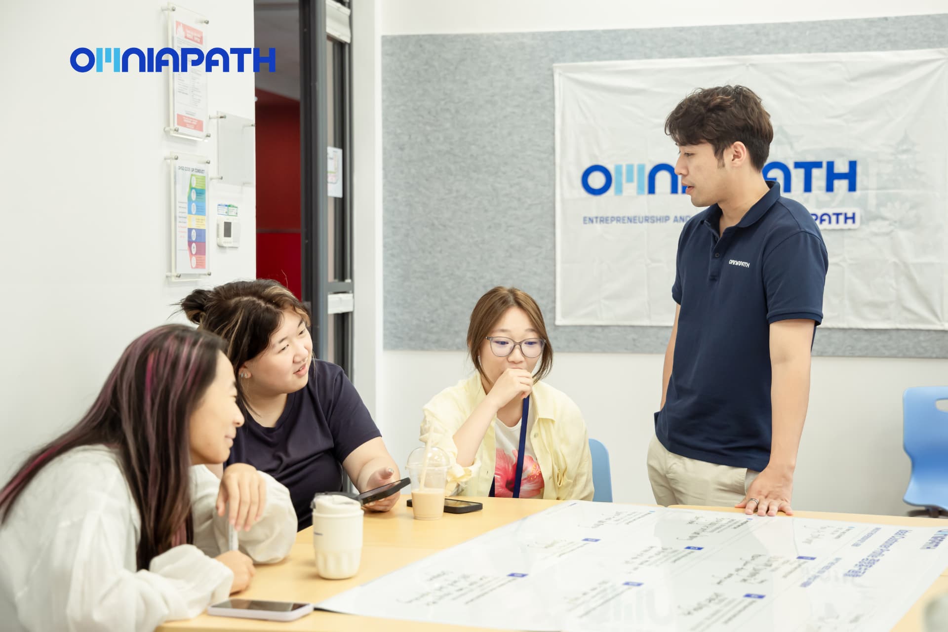 A mentor guiding students around their venture canvas table